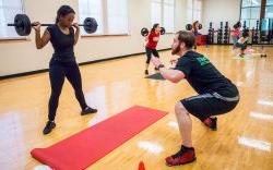 Fitness instructor teaching another how to do squats