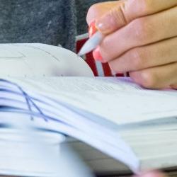 Close up of a book and a student writing.