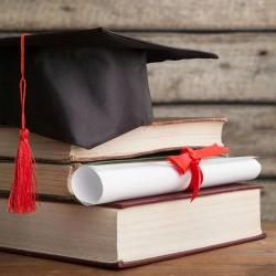 Image of a stack of books with a diploma and a graduation cap.