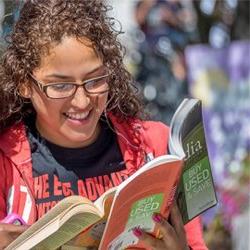 photo of female student looking at a book and smiling