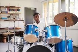 Male Teenage Pupil Playing Drums In Music