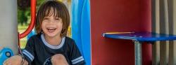 Image of a smiling child sitting on playground equipment.