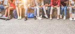 Photo of young adults sitting in group drinking coffee and using their cellphones.