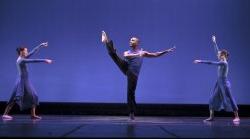 Photo of pirouetting dancer surrounded by two more performers