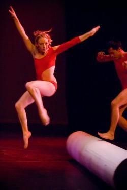 Photo of dancers in leotards jumping over a stage decoration