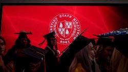 Montclair State University shield shown with the silhouettes of graduating students in the foreground